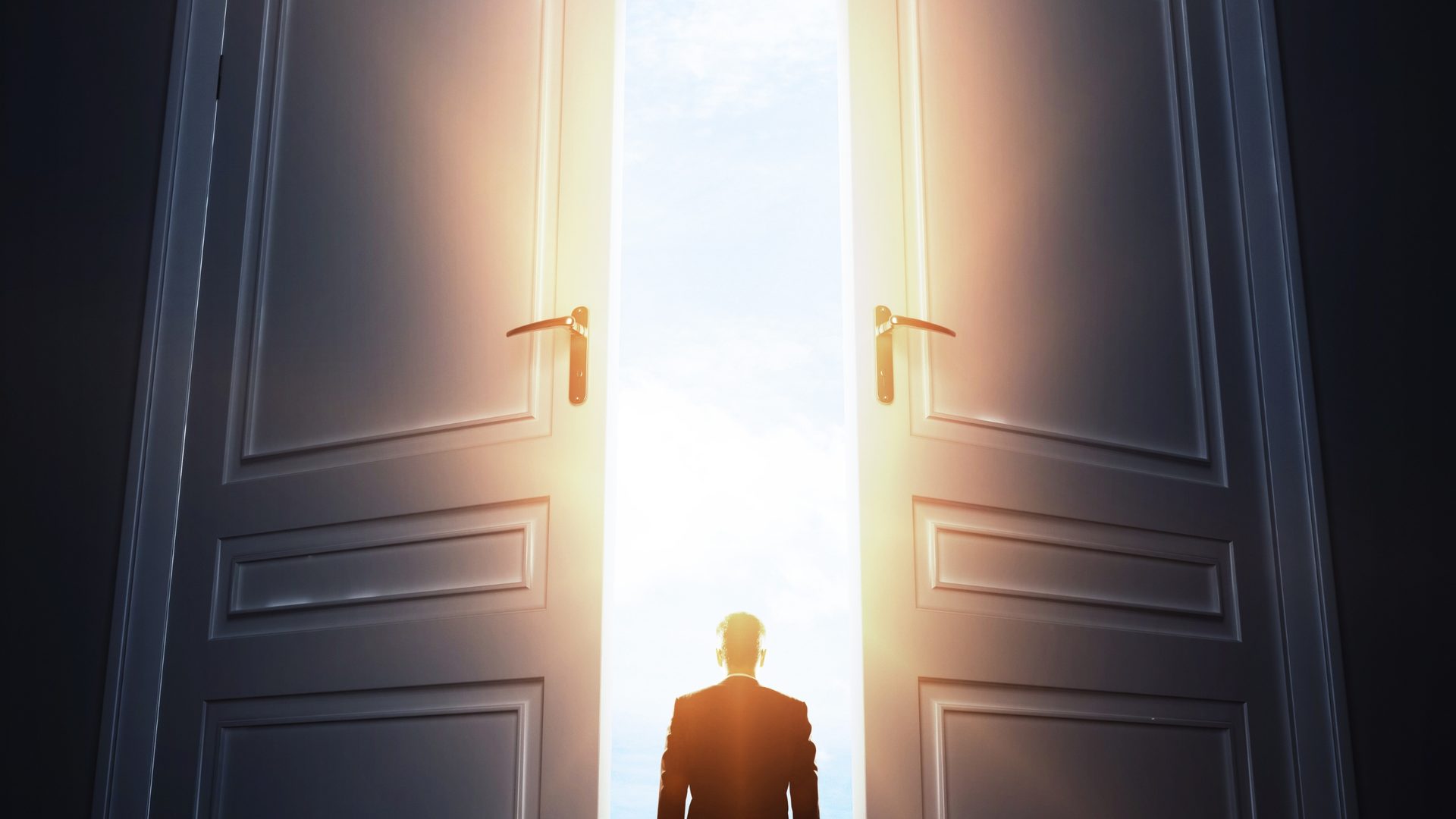 A figure stepping through open doors into bright light
