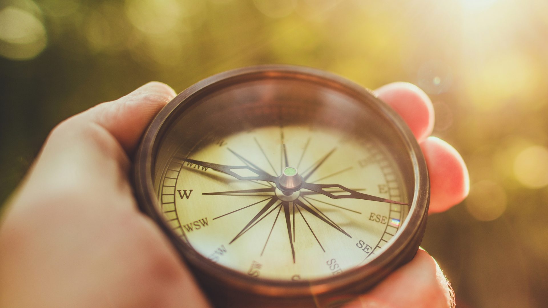 A hand holding a compass in warm sunlight, symbolizing regained direction and conviction